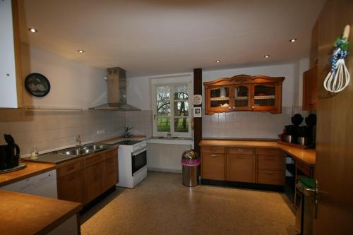 a large kitchen with wooden cabinets and a sink at Erlenhof-Steinau-Fachwerkhaus-mit-Reetdach in Steinau