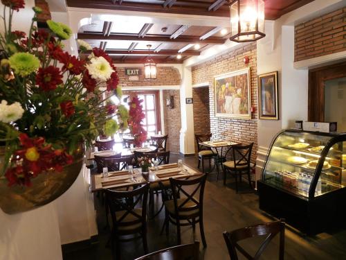 Ciudad Fernandina Hotel في فيغان: مطعم به طاولات وكراسي و إناء من الزهور