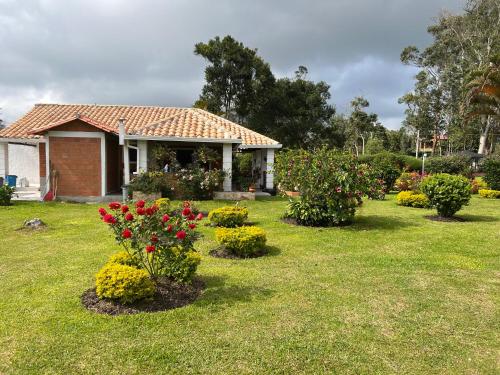 a house with flowers in front of a yard at Hermosa Cabana con bonito Jardin y piscina en la Mesa de los Santos in Los Curos