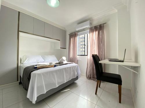 een slaapkamer met een bed en een bureau met een laptop bij BK54 - Climatizado, TV Smart, Conforto, Garagem in Balneário Camboriú
