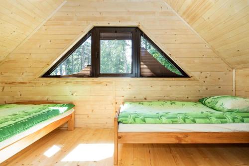 two beds in a wooden cabin with a window at Holiday complex, Pobierowo in Pobierowo
