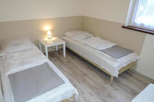 a room with two beds and a table with a lamp at Semi-detached house, Kolczewo in Kołczewo