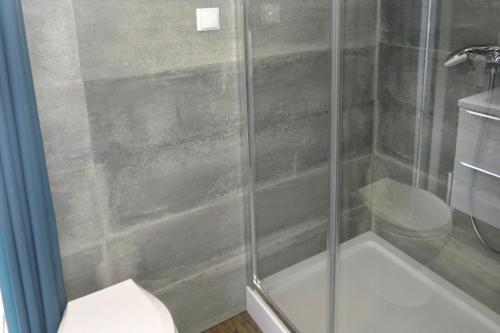 a shower with a glass door next to a toilet at Bungalows, Dziwnow in Dziwnów