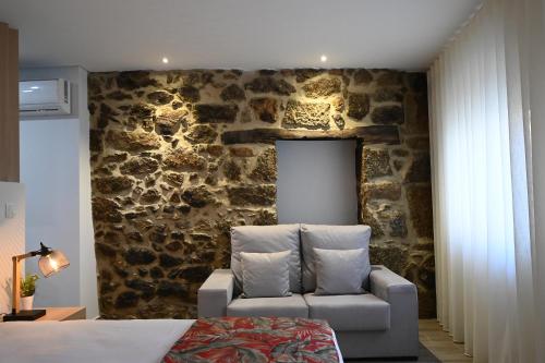 una camera da letto con parete in pietra, divano e sedia di O Visconde - Alojamento local a Lamego