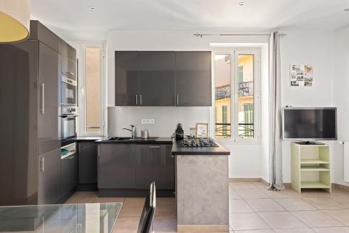 une cuisine avec des armoires noires et un comptoir dans l'établissement Appartement 2P centre de Cannes avec balcon, à Cannes