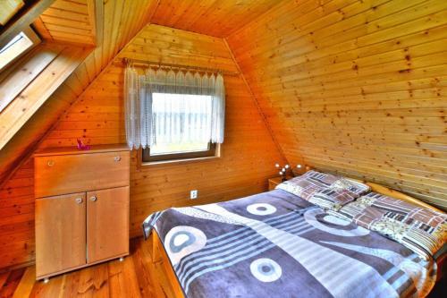 een slaapkamer met een bed in een houten hut bij holiday home, Swiecianowo 