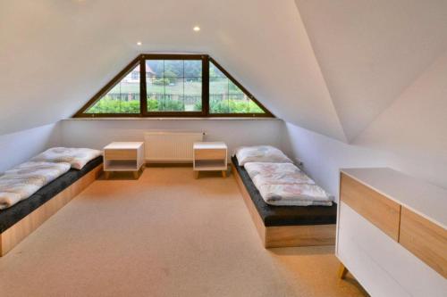 a attic room with two beds and a window at Villa in wi cianowo near Ostrowieckie Lake in Zegocino