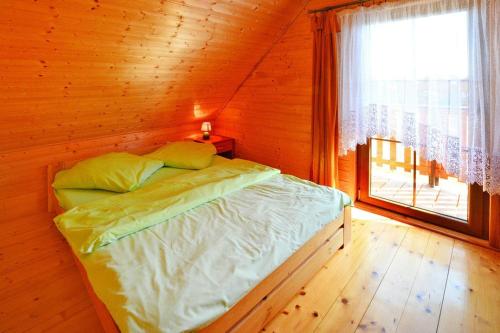 Cama en habitación de madera con ventana en Holiday resort, Jaroslawiec, en Jarosławiec
