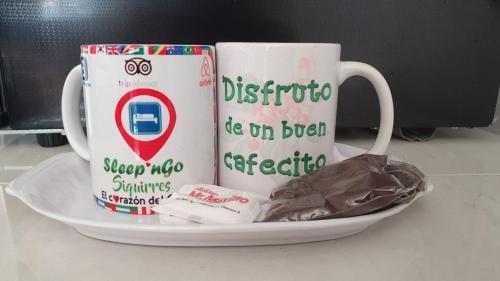 two coffee mugs on a plate on a table at Sleep&Go! Apartamento 2 habitaciones 4 personas Siquirres centro in Siquirres