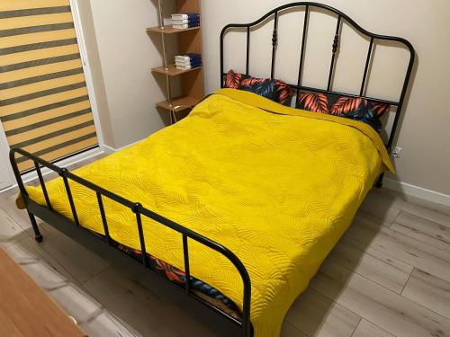 a bed with a yellow blanket on top of it at Apartament Puscha in Kielce