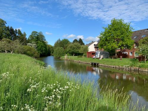 a river in a village with grass and flowers at Ferienwohnungen direkt am Wasser in Glückstadt in Glückstadt