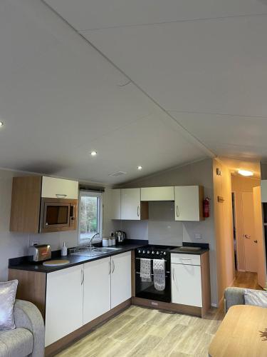 a small kitchen with white cabinets and a couch at Coastal retreats, Beech rise, primrose valley in Filey