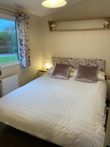 1 dormitorio con 1 cama blanca y 2 almohadas en Coastal retreats, Beech rise, primrose valley en Filey