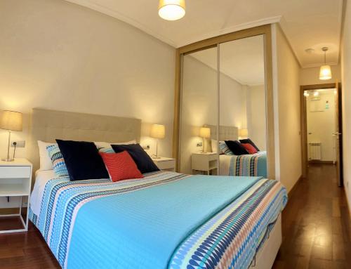 1 dormitorio con 1 cama grande y espejo en Apartamento Europa Prados - Atenea, en Oviedo