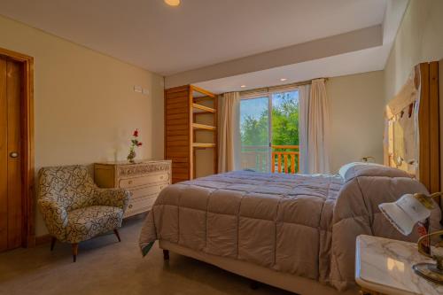 a bedroom with a bed and a chair and a window at Hotel de campo Haras Los Abuelos in Sierra de los Padres