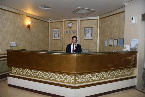 a man in a suit sitting at a reception desk at Continental Suite farwaniya in Kuwait