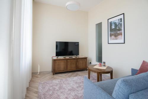 een woonkamer met een blauwe bank en een tv bij Klevų apartamentai in Klaipėda