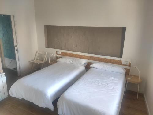2 camas en una habitación de hotel con sábanas blancas en Casa Espanyoleto, en Xàtiva