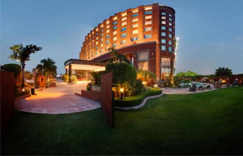 un grande edificio con un prato di fronte di Radisson Blu MBD Hotel Noida a Noida