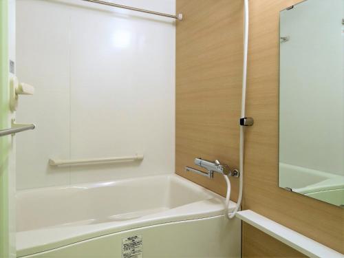 a bathroom with a bath tub and a mirror at Green Rich Hotel Kyoto Station South (Artificial hot spring Futamata Yunohana) in Kyoto