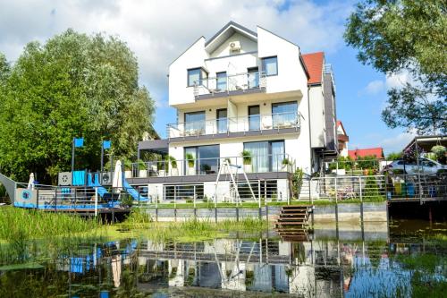 a white house with a pond in front of it at Cobalt Apartments in Mikołajki
