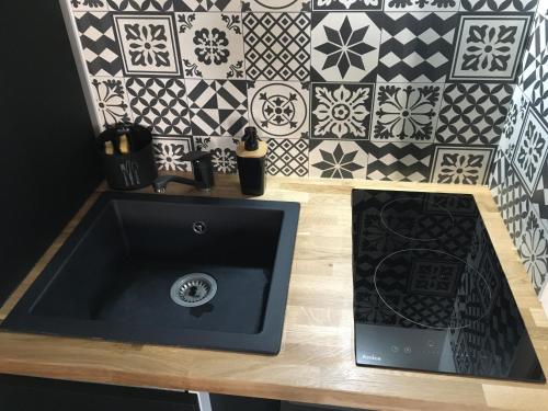 a bathroom with a sink and a tile wall at Studio 15 in Honfleur