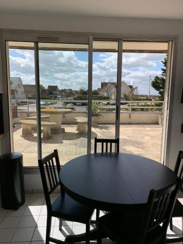 une table et des chaises devant une grande fenêtre dans l'établissement Appartement vue sur mer courseulles, à Courseulles-sur-Mer