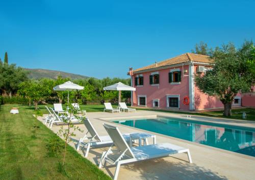 a swimming pool with lounge chairs and a house at Doliva Estate in Laganas