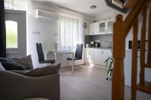 a living room with a table and chairs and a kitchen at Marietta Apartman in Hévíz