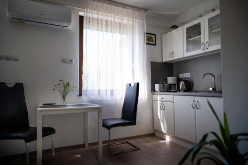 a kitchen with a table and chairs and a window at Marietta Apartman in Hévíz