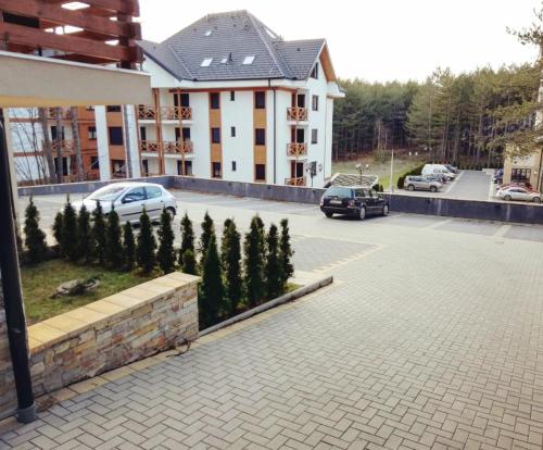 a parking lot with cars parked in front of a building at Apartman Pineta in Zlatibor