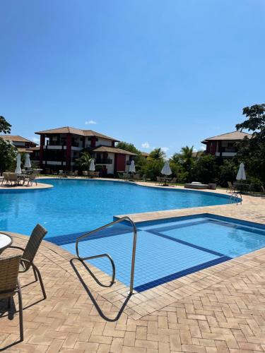 ein großer Swimmingpool mit Stühlen und Tischen in der Unterkunft Apartamento 3/4 maravilhoso no Village das Acácias in Praia do Forte