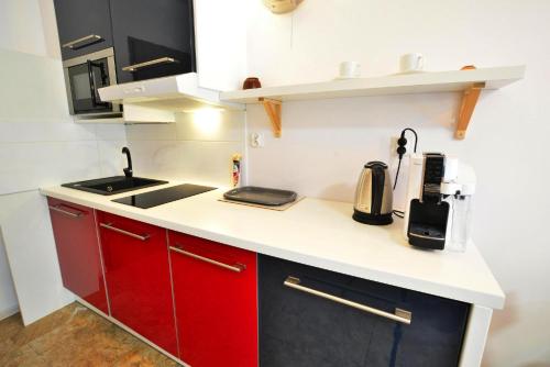 a small kitchen with red cabinets and a sink at Studios, Mielno in Mielno