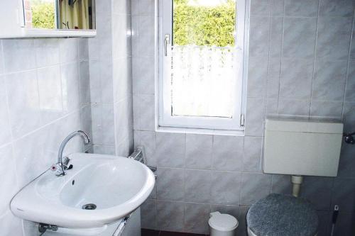 a white bathroom with a sink and a window at Holiday home, Plau am See in Plau am See