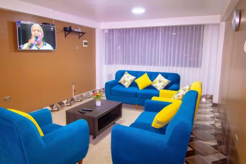 a living room with blue couches and a tv at Departamentos KIRI para familias o empresas que viajan en grupo cerca al Aeropuerto Juliaca in Juliaca