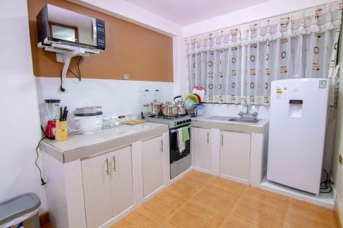 a kitchen with white cabinets and a white refrigerator at Departamentos KIRI para familias o empresas que viajan en grupo cerca al Aeropuerto Juliaca in Juliaca