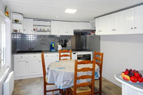 une cuisine avec des armoires blanches et une table et des chaises dans l'établissement Holiday Home in Plourivo near Goëlo Coast, à Plourivo