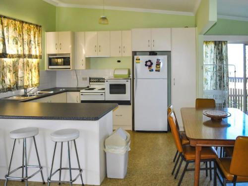 a kitchen with a refrigerator and a table and chairs at 2 Rockpool Road in Tuncurry