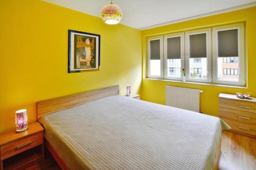 żółta sypialnia z łóżkiem i 2 oknami w obiekcie Apartment, Kolobrzeg w Kołobrzegu