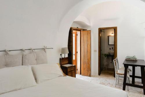 una camera con letto bianco, scrivania e tavolo di Trullo, Cisternino a Cisternino