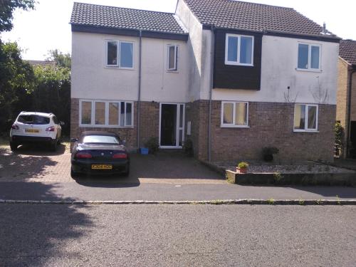 a house with two cars parked in front of it at Carters Guesthouse in Milton Keynes