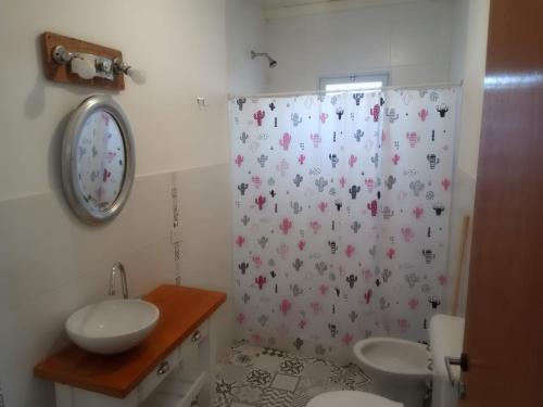 a bathroom with a sink and a shower curtain with flowers at Luz de las Sierras in Arroyo de Los Patos
