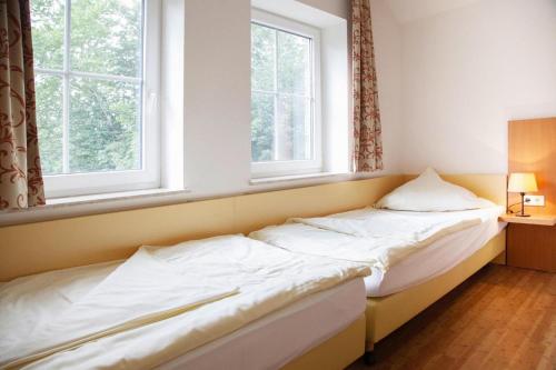 a bed in a room with two windows at Ferienhäuser in Greetsiel in Greetsiel