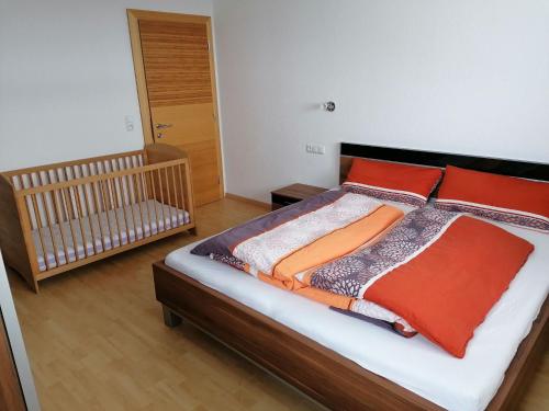 a bedroom with a bed with red pillows and a crib at Holiday home Hart im Zillertal in Hart im Zillertal