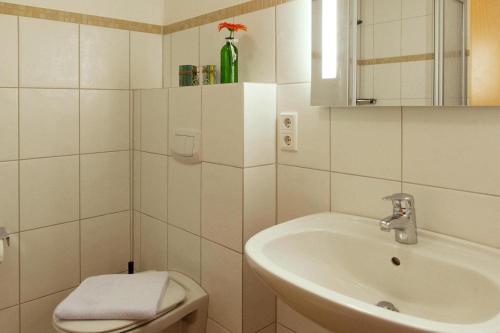 a white bathroom with a sink and a toilet at Ferienhäuser in Greetsiel in Greetsiel