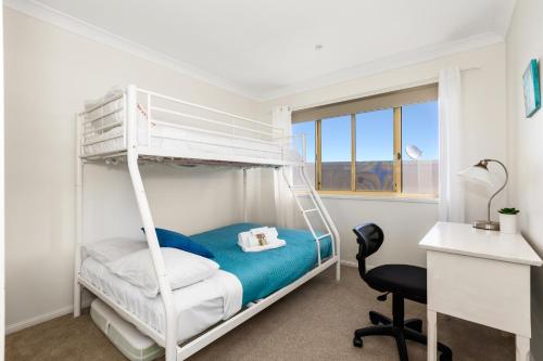 a bedroom with a bunk bed and a desk at Hungerford Beach Apartment by Kingscliff Accommodation in Kingscliff