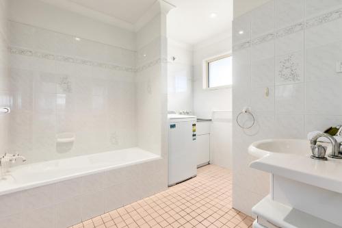 a white bathroom with a tub and a sink at Hungerford Beach Apartment by Kingscliff Accommodation in Kingscliff