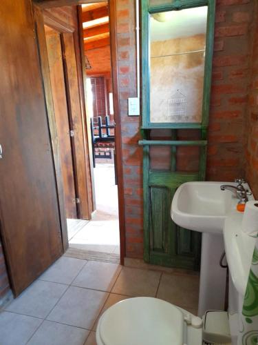 a bathroom with a toilet and a sink and a door at Cabaña EL ZORZAL de Villa del Dique in Villa del Dique