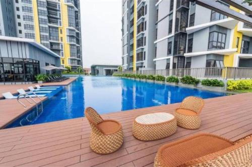 a patio with chairs and a swimming pool with buildings at Cozy Mayfair Homestay in Puchong