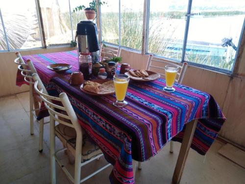 una mesa con zumo de naranja y una cafetera en ella en Uros Suyawi Titicaca Lodge en Puno